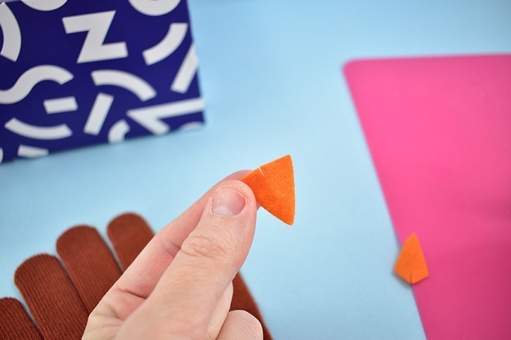 Cut a triangle shape out of orange felt for the turkey's beak. Cut a small slit in the middle where it will connect with the face.