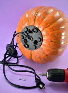 Use small screws (whatever you have on hand that will fit in the holes that will work) to attach the lamp base to the pumpkin. Remove the assembly and place your screws somewhere you can easily find them again.