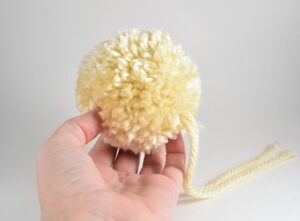 Want to add some super cute warmth to your favorite room? Make fuzzy pom poms to put on a store bought blanket for the ultimate throw!