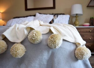 Want to add some super cute warmth to your favorite room? Make fuzzy pom poms to put on a store bought blanket for the ultimate throw!