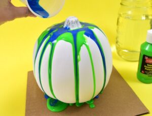 These colorful, drippy no carve pour art pumpkins are super easy and use washable paint making it the perfect Halloween kid craft! Click through for a few tips and tricks so you can achieve pretty results!