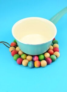 Save your tabletops and counters from unnecessary burns with an easy to make wooden bead trivet. Paint, dye or leave the beads natural to match any kitchen