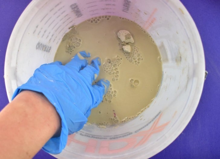 Place dry cement powder in a plastic pail. Add a small amount of water and mix thoroughly with gloved hands.