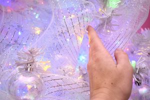 The liberal use of white decomesh with silver striping not only fills out the tree, but also helps to reflect the light, adding to the soft rainbow effect the tree creates.