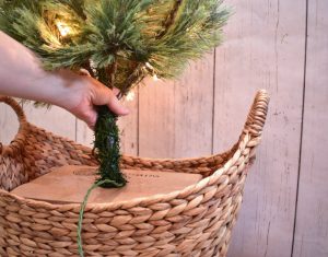 With your cardboard box snugly in place, shove the pole end of the tree into the X cut on the top of the box. You might have to remove the plastic base pieces the tree comes with, but they should easily slide off.