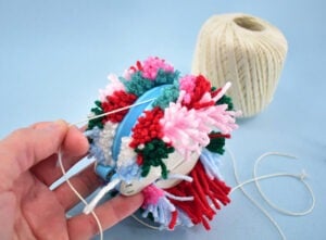 Take a piece of yarn or other string and wrap it in the middle of the maker pulling it as tight as you can. Wrap and knot this cord several times to secure.