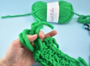 Reach in through the loop and grab the ends of the yarn. Pull through.