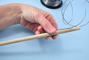 Hold about an inch of wire along a wood dowel.