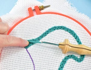 When you're ready to change yarn it's a really simple swap. After you've made the last stitch push your finger onto the needle and yarn beneath as you pull out the punch needle. Be sure to keep constant pressure on that last stitch as you pull the needle free of the fabric.