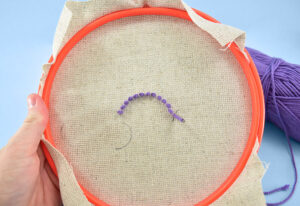 Load up your punch needle with purple yarn and begin working from bottom center ring of the rainbow upward.