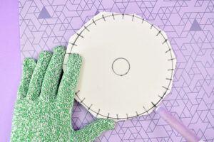(Follow the first 4 steps of the cardboard disk tutorial) Print out your PDF pattern and cut the disk shape out along the outermost circle. Place on top of your foam and trace the circle using a felt tip pen or fine tip marker. Cut the pattern down to the next circle and place it in the center of the first circle you drew. Follow the lines on the pattern to draw the cord slots around the disks edge. Cut the pattern down to the innermost circle, place in the center of the foam and trace. Using a sharp craft knife trim away the excess foam from the outer circle. Next use the craft knife to cut the slots around the disk's outer edge. Cut away the inner circle with the craft knife as well.