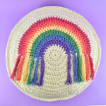 Looking for a fun, colorful, and fringed DIY addition to your decor? Get the free pattern and hook up this round crochet rainbow pillow!