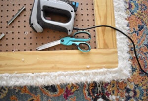 Repeat the process with the faux fur material but tack it to the side of the wood frame rather than to the pegboard.