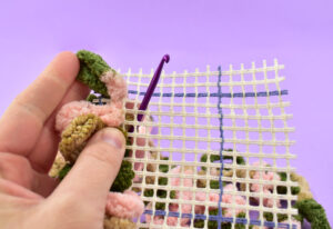 Work your first row of loops in a straight line along the canvas. A rug canvas with a grid makes this a little easier. When you finish your first row, turn and skip the row immediately next to the one you just looped up. Start hooking your loops through after the skipped row.