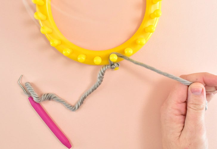 Wrap the yarn around the first peg in line with your tied knot in a clockwise fashion.