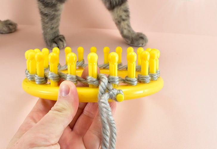 Holding your last wrap in place, push the yarn to the base of the loom on all pegs.