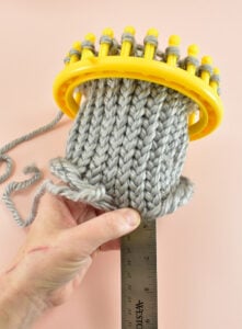 When you've taken off all of the loops, repeat the knitting process... Push the loops on the pegs down to the loom's base. Wrap the yarn around each peg until you reach the last. Holding the last loop in place, hook the bottom loop with your tool and pull over the the top loop and off of the peg.  Continue until you knit approximately 6" of length for a short, squatty pumpkin and up to 10" for taller pumpkins.
