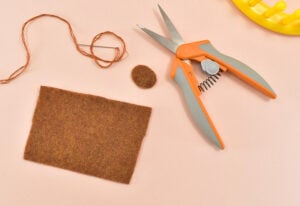 From a piece of brown felt cut a circle approximately the size of a quarter and a rectangle that measures 2" x 3.5". Thread and embroidery needle with matching floss.