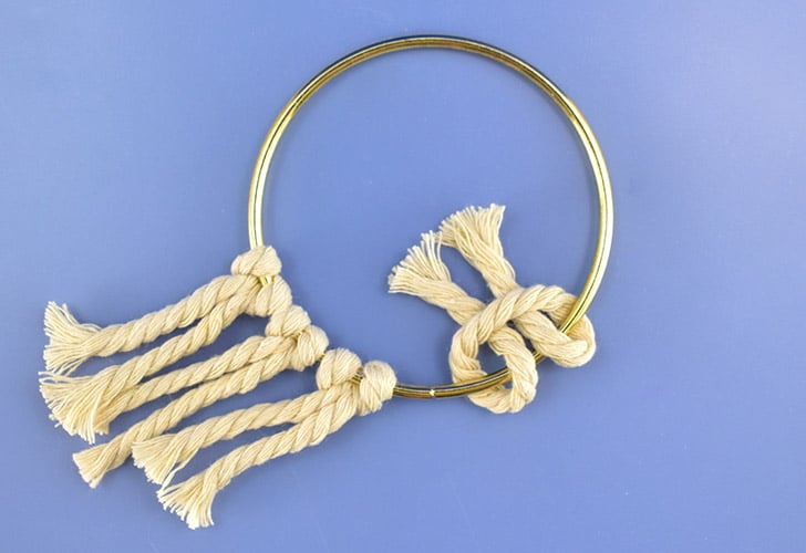 Pull the 2 legs of the cord over the brass hoop and through the curve of the cord.