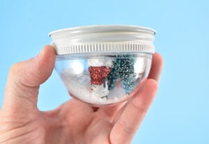 Flip the lid over and place into ornament holding the Buffalo snow. Shake the snow around to make sure it isn't stuck between the plastic surface of the globe and the ornaments with a little shake.