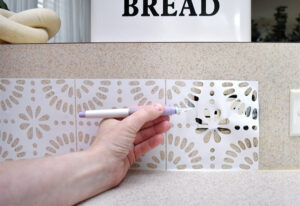 When you get to an outlet, apply your tile as much as possible to the backsplash surrounding the outlet. Use your knife with a sharp blade to carefully trim away any vinyl that sits on top of the box. Another quick reminder, be double sure the power is off so you don't zap yourself.