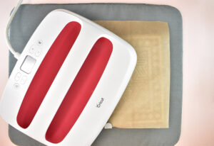Using an EasyPress or your household iron, apply heat and pressure to the design. (For your Easypress use the setting of 300 degrees and 25 seconds).