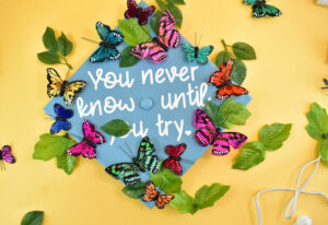 Start pushing the leaves of artificial greenery around and under the butterflies and glue down.