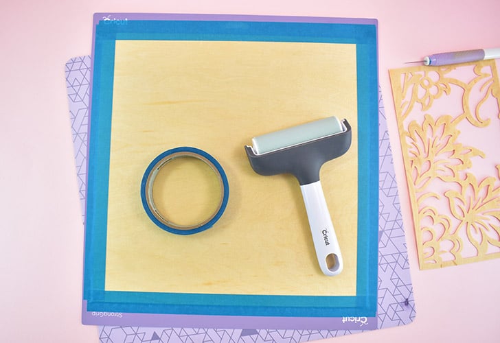 Apply a piece of veneer to a StrongGrip cutting mat. Use a brayer to fully attach the wood and then tape around the edges to ensure it stays in place during cutting.