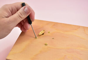 Gently screw through the holes in the bottom into the mechanism to hold in place. Do not overtighten screws or you could risk stripping them.