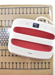 Preheat your EasyPress 2 to 230° at 30 seconds. Place the press directly on top of the carrier sheet of your design and apply gentle pressure. Pick up the press and repeat to tack down all sections of the design. Do not remove the carrier sheet until all of the design has been set.