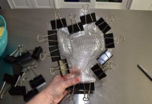 Using a pair of strong scissors, trim around the two sides of the mold together at the same time. Make sure you cut away enough that the clip clamps right up to the edge of the design, but not so close you don't have enough to clamp onto.