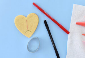 Take an edible marker and draw guidelines on the top of a cool cookie. First create the semi-circle for the head at the tip of the heart. Next draw a line down the middle to separate the two wings. Be sure to only draw where you will actually ice the cookies. You don't want little lines peeking out beside the design.