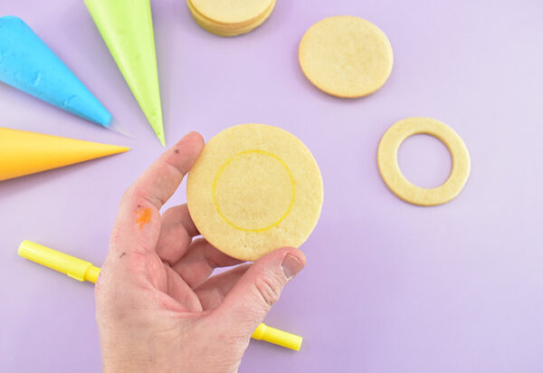 Place your center cookie on top of a solid circle. Use an edible marker to trace the inside shape of the cookie.
