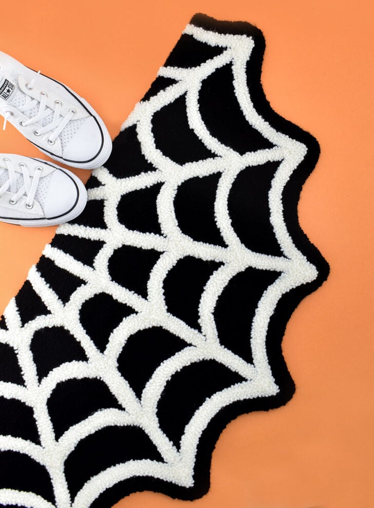 A little bit spooky and a whole lot cute, grab the free pattern to make your own Spiderweb Punch Needle Rug!