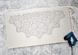 Place your monk's cloth with the design transferred to it onto your frame, centering as well as you can. Tack the cloth around every inch or two using your staple gun, stretching the cloth just enough to keep it nice and taut on the frame. Wrap the cloth around to the back of the frame and tack down again.