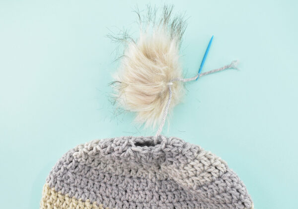 See that little hole at the top of the hat? We're going to need to close that up with the tail. Note* If adding a pompom you can string it onto your tail either before (as pictured above) or after closing this top hole.