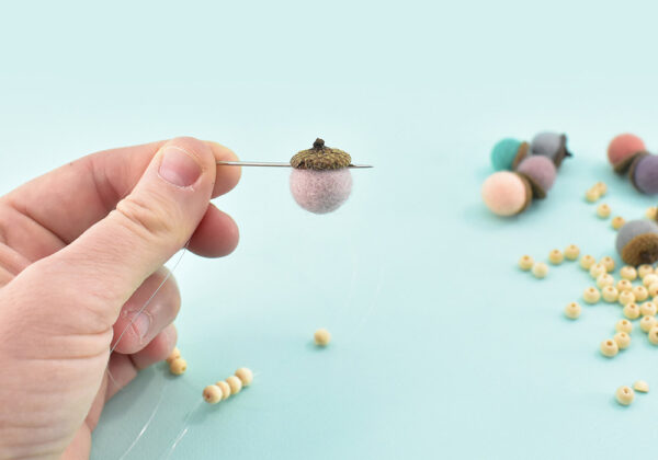 Run the needle as close to the cap through the felt ball as you can so that it stays upright. Running the needle through the center or lower and the weight of the cap and glue will turn the acorn upside down.