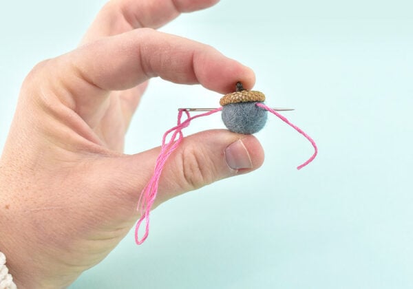 To start with an acorn rather than a bead, run the string through the acorn near the cap. Move the needle over slightly and run back through in the other direction and pull tight, holding onto the tail so that it doesn't pull through the acorn. Run the needle through a third time and pull taut. The acorn should stay in place and not move.