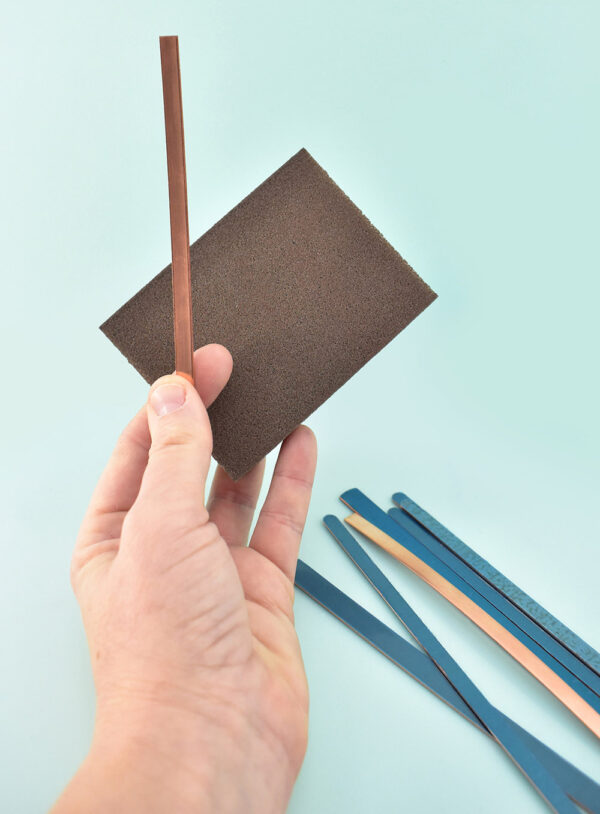 Using a very fine grit sanding sponge or sandpaper buff the top layer of copper on both sides of the bangle. Your copper will go from a deep orangey color to a much lighter pinkish color. Use a clean, slightly damp rag to remove any dust and allow to dry.