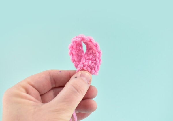 Separate out your different sized strips and work with one size at a time. Taking a crochet strip fold the top toward the bottom in a clock-wise sweeping motion. Match up the bottom edges. This will form a loop that looks kind of like a cause ribbon.