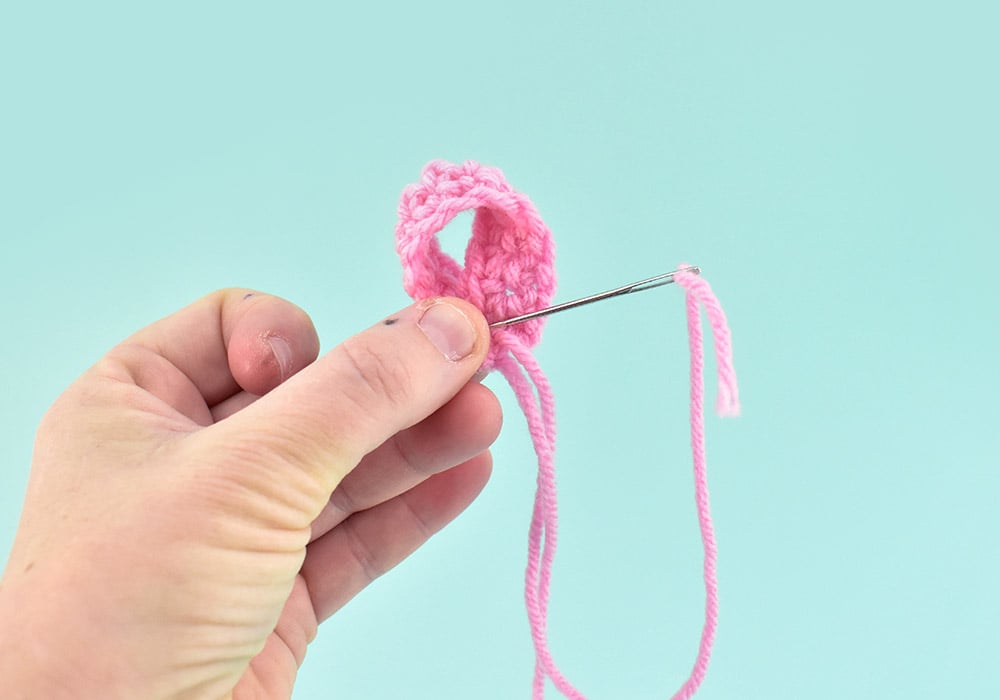 Using one of the tails stitch the 2 ends together, making sure you don't lose that loop shape as you go. You don't need a lot of stitches, just run from one side to the other so that both tails are on the same side.
