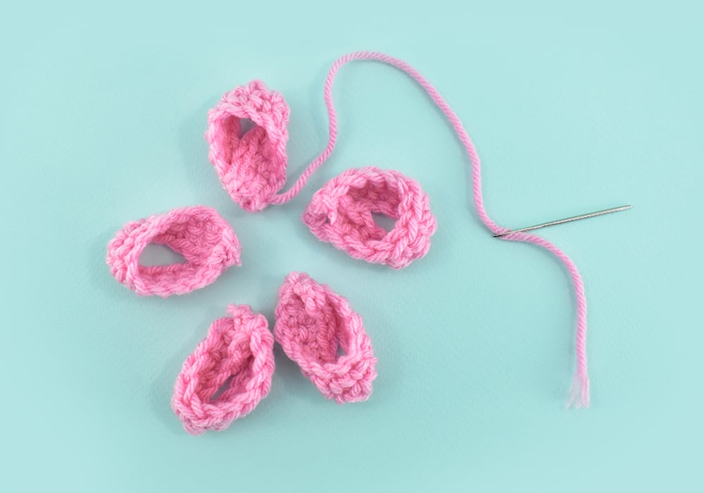 Trim all but the longest tail from your 5 points of the bottom-most (largest) bow layer. Run a steel yarn needle onto that tail to sew your 5 points together into one layer.