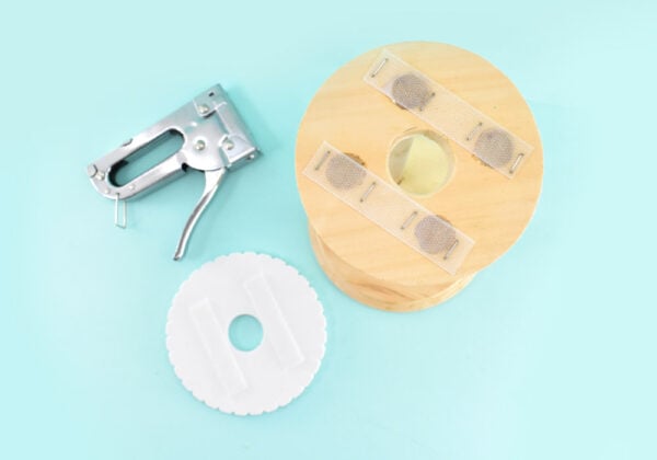 Grab some self-adhesive Velcro and peel to reveal the sticky and stick the scratchy side onto the top of your Kumi stand. Tack down with a staple gun to hold the Velcro firmly in place. Match up the the softer, fuzzy side of the Velcro onto the strips on your stand. Remove the plastic to reveal the sticky. Push your Kumihimo disk directly onto the the sticky side of the Velcro, matching up the center hole of the disk with the center hole of the stand. Gently pull off the disk and go over the Velcro with some pressure to really make sure that sucker is going to stick.
