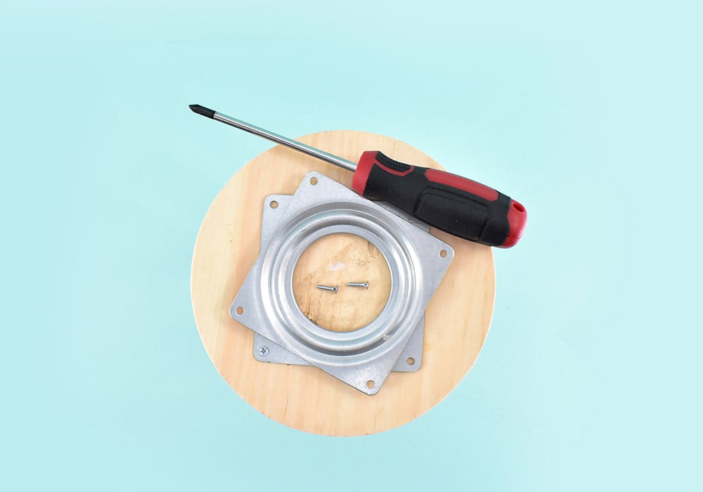 Flip your stand over so that the bottom is facing up. Twist apart the two pieces of the lazy susan hardware so you can see the screw holes on the bottom piece. Using a screwdriver and #4 - 1/2 wood screws, attach the plate to approximately the center of the stand.